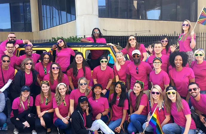 A group of employees don pink t-shirts and wave rainbow flags in a showing of solidarity for the LGBTQ community.