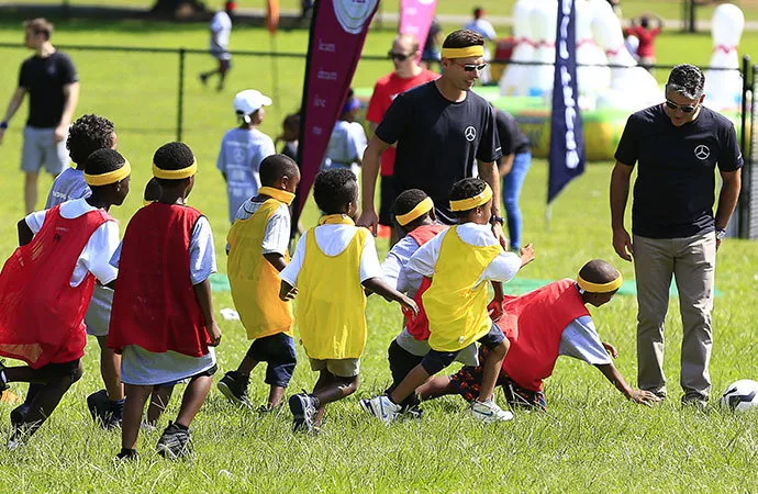A group of children enjoy a game of soccer, facilitated by Mercedes-Benz volunteers.