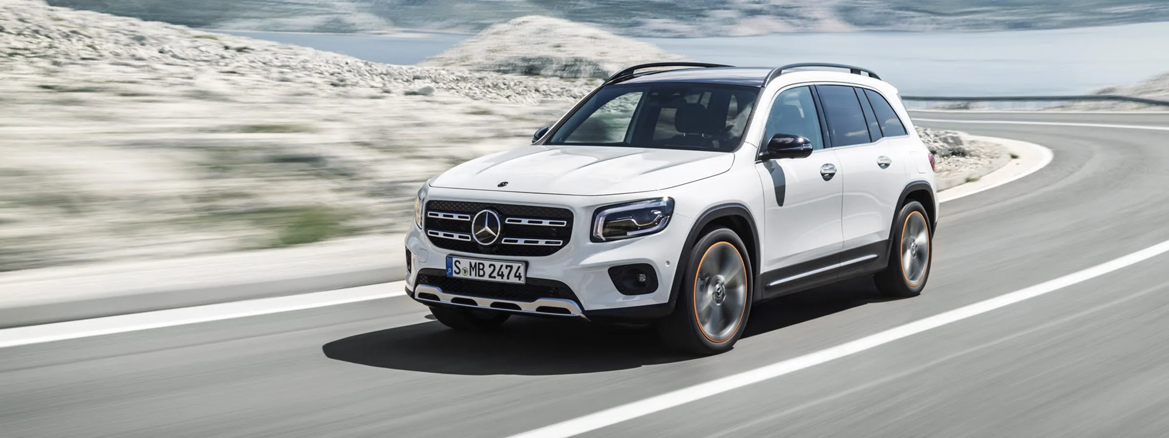 White GLB SUV driving along curved road