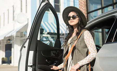 A young woman steps out of the driver’s side of her Mercedes-Benz.