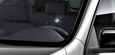 A close-up of a crack in the corner of a windshield.