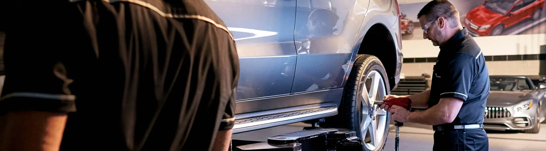 A certified service technician works on the wheel of a Mercedes-Benz.