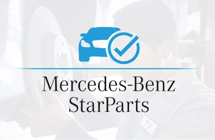 A person with a towel wipes down the top of an engine near the Mercedes-Benz logo.