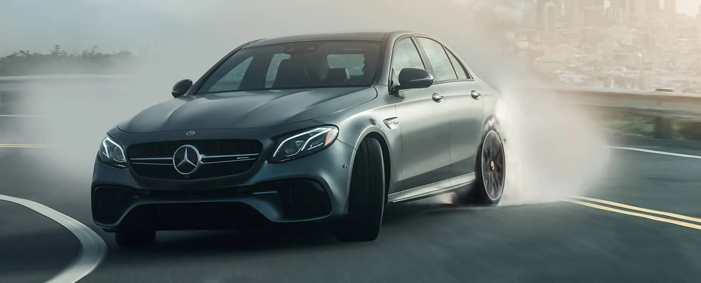 A matte-gray Mercedes-AMG vehicle takes a sharp turn at speed.