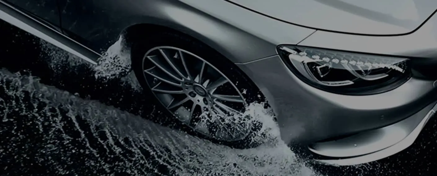 A silver Mercedes drives through a few inches of water.