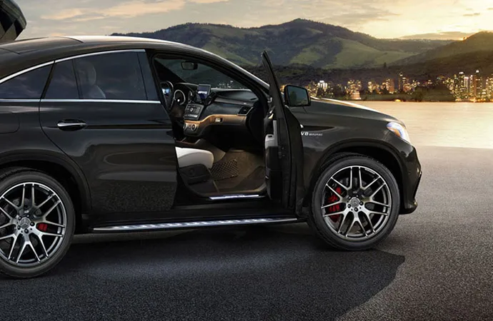 A black SUV is parked at a scenic overlook with its passenger door open.