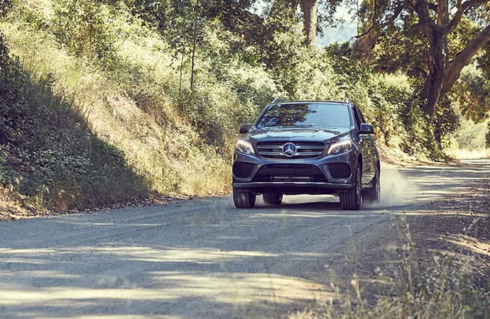 A Mercedes-Benz SUV is driven along a dirt road.